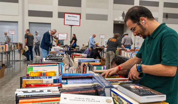 A man looking through a pile of organized books on a table