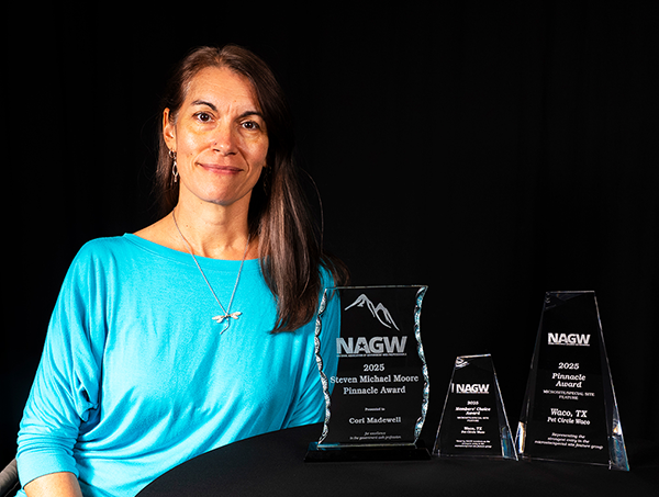 Cori Madewell sitting with three awards