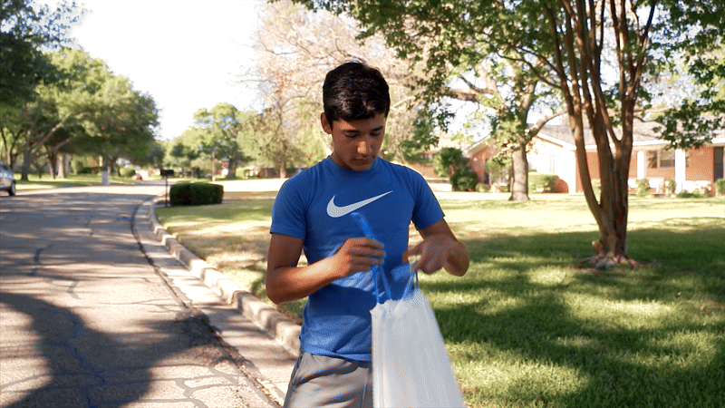 Teenage boy tying a trash bag