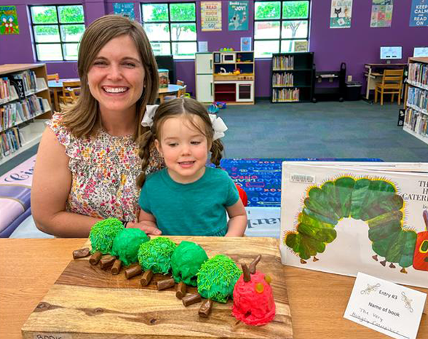 A mom and her young daughter displaying their Very Hungry Caterpillar cake