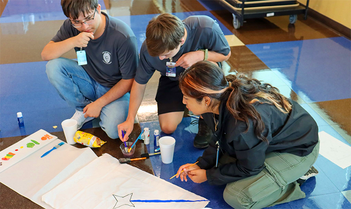 Three teenagers drawing and painting on the floor