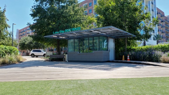 An exterior photo of Lakes Edge boat house with the dock and waters of Lake Woodlands visible. 