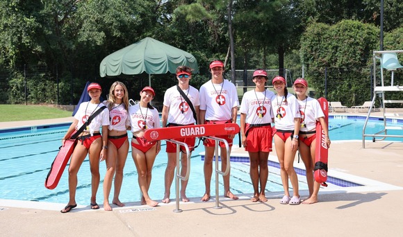 Lifeguards in The Woodlands Texas pose in uniform in front of an area pool