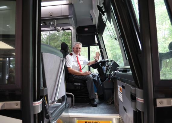 Photo of a smiling city bus driver sitting in the front of the bus