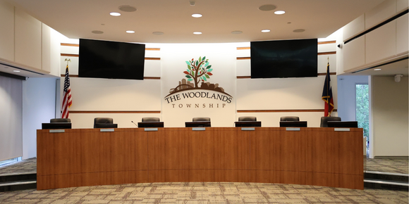 Photo of empty Boardroom with wooden dais and black high back chairs