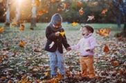 young boy and girl playing with leaves in autumn