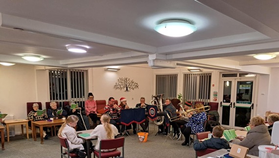 A group of people playing brass instruments and singing carols 