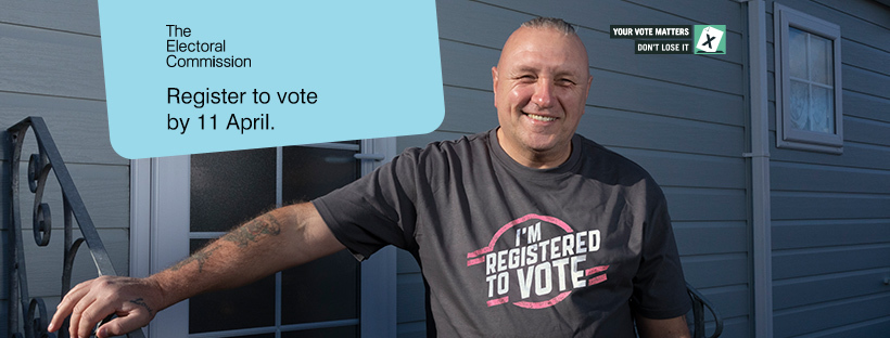 Smiling man next to banner that states Register to vote by 11 April