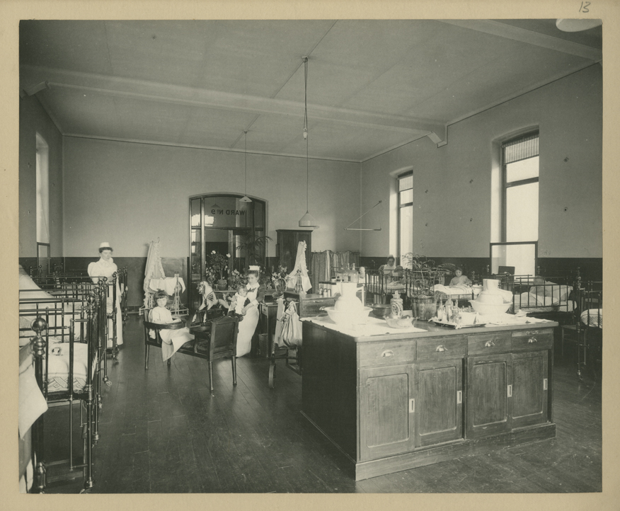 Black & white photo: Interior view showing nurses with children in Children's Surgical Ward, cots and a rocking horse are also visible.11/1309]
