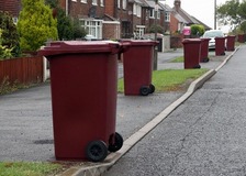 Burgundy bins waiting for collection in a street