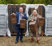 Two people holding new brown bins