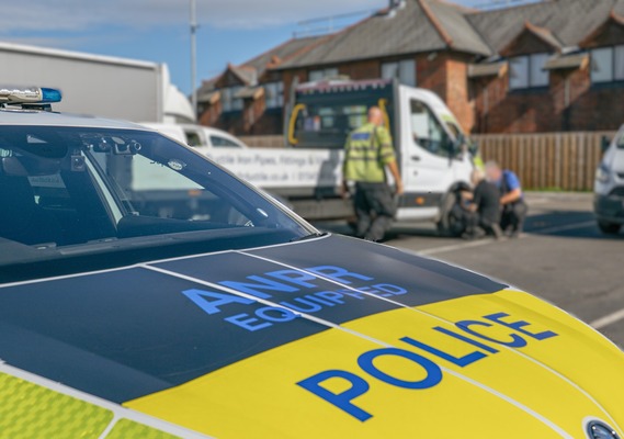 Police vehicle with officers in the background checking a vehicle