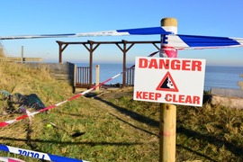 A hazard sign, outside on a sunny day. The sign says 'subsidence'.