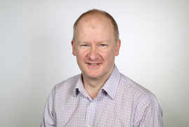 A head and shoulder shot of Dr Gavin Mudd, who wears a light lilac shirt, and smiles at the camera. 