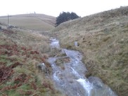An image of a river flowing downhill in a small valley as we monitor storm water runoff.