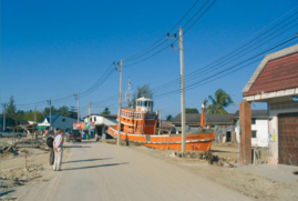 Damage caused in Thailand by the Indian Ocean tsunami. A large lifeboat sits on the side of the road, after being washed ashore. 