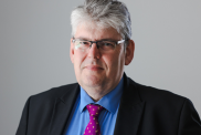 A headshot of Paul Monks, wearing a suit, blue shirt and purple tie