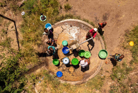 A group of individuals congregated around a well in the village of Quionga, Mozambique. (c)iStock