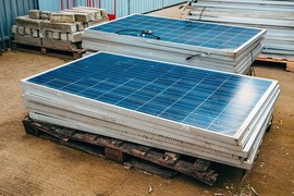 Two stacks of photovoltaic panels sit on wooden pallets