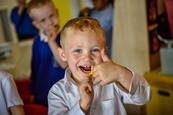 Photograph of a young boy brushing his teeth and giving a thumbs up sign