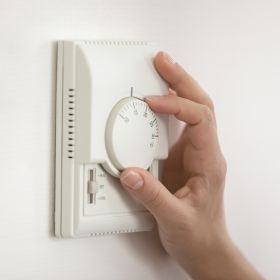 Photo of someone turning their thermostat up or down