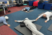 Photo of a group of men laying on the floor on exercise mats stretching