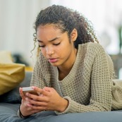 Photo of a teenage girl reading something on her phone