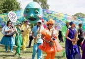 Photo of a people dressed up in bright colours playing instruments in the park