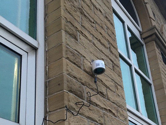 An image of a purpleair sensor mounted on the side of a building