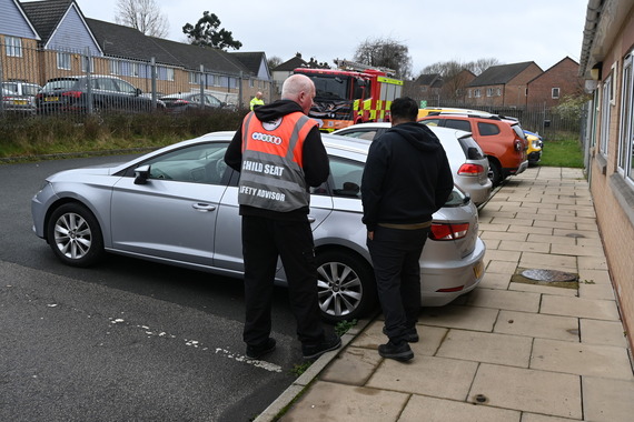 photo of 2 men at side of a car checking if child seat is fitted correctly