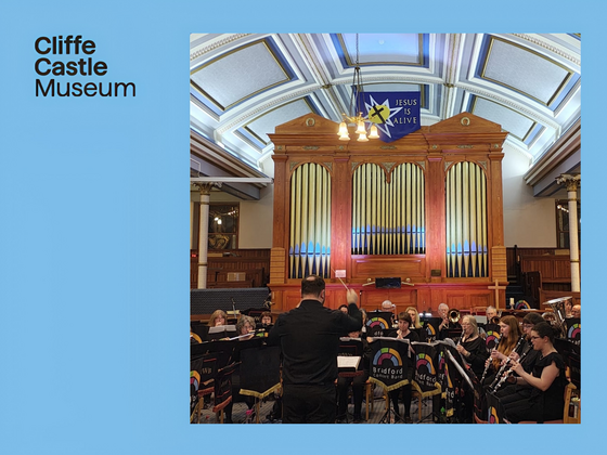 Bradford Concert Band performing in a grand hall with a pipe organ behind them.
