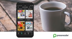 PressReader displayed on a phone next to a couple of coffee