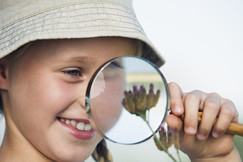 Young girl viewing a flower through a magnifying glass