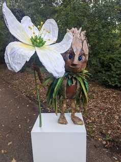 Sprite sculpture holding a flower, in a park setting