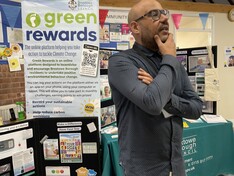staff member at a community event infront of a pop up info stall