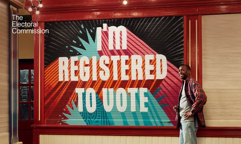 Man standing next to an 'I'm registered to vote' sign
