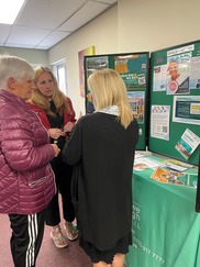 three people talk infront of a table with information about broxtowe borough council housing