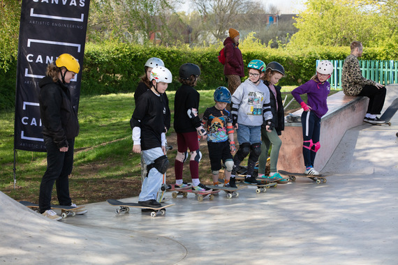 Children lining up with skateboards at the edge of a ramp