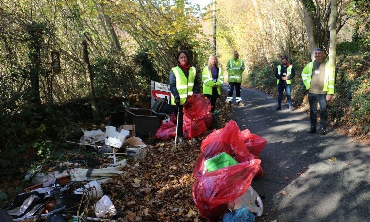 Leader of Council and other volunteers stand around bags of rubbish in the countryside