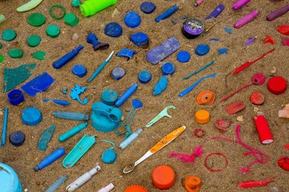 Mutli coloured plastic waste arranged on sand