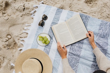 A book on the beach with a sun hat.
