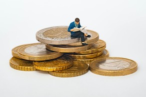 A figure sitting on a pile of coins while reading a book.