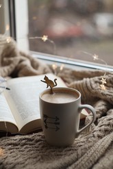 A mug of hot chocolate in front of an open book.