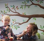 Young children and tutor eating cakes together.