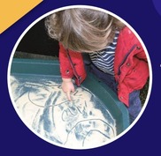 A young child using their fingers to draw in sand