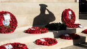 Poppy wreaths laid out on a set of steps with the shadow of a saluting soldier in the background