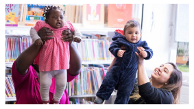 Two parents holding children during Rhyme time in a library