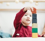 a young child building a tower with wooden blocks