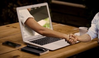 Helping hand emerging from a laptop screen
