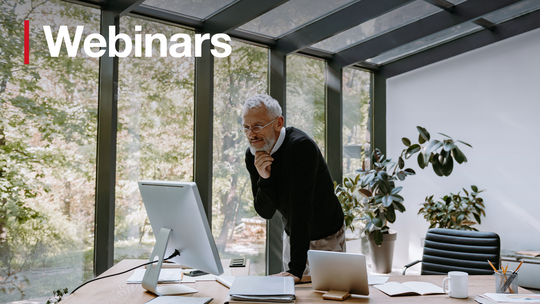 A man leaning over a desk looking at a screen. Text reads: Webinars